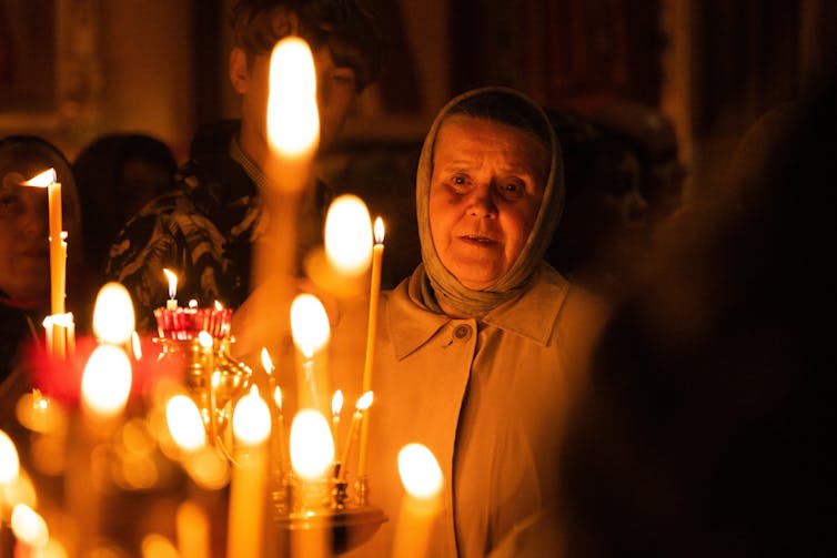 An elderly woman prays in a Russian Orthodox church.