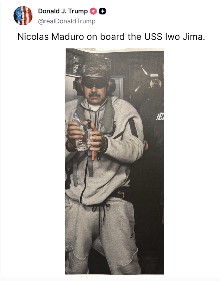 A man wearing sweatpants and a sweatshirt, in handcuffs and blindfolded.