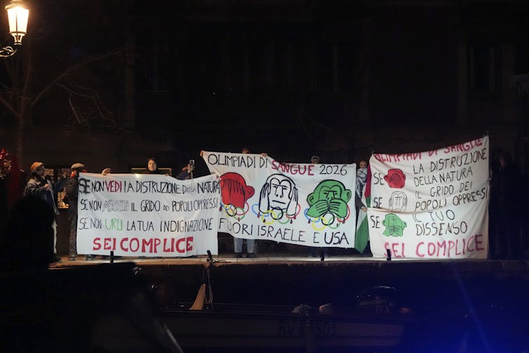 People holding protest signs along the banks of a canal