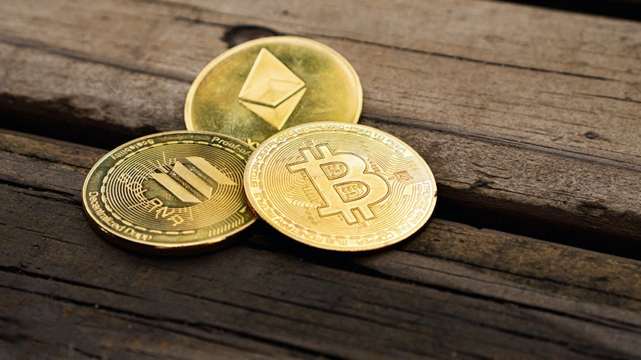 Gold crypto coins on a wooden surface.