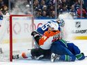 Canucks goaltender Thatcher Demko braces for impact as Elias Pettersson and the Philadelphia Flyers' Owen Tippett slide into the net in yet another home loss on Dec. 30, 2025.
