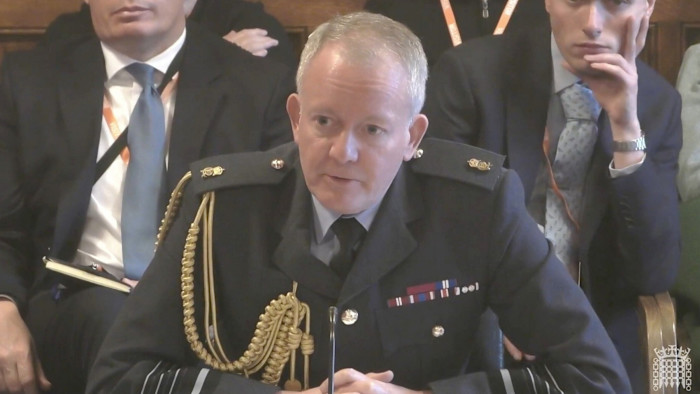 Air Chief Marshal Sir Richard Knighton sits in uniform at a table, speaking during a Defence Committee session.
