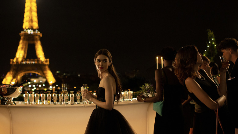 Emily getting champagne from a bar overlooking the Eiffel Tower in Emily in Paris