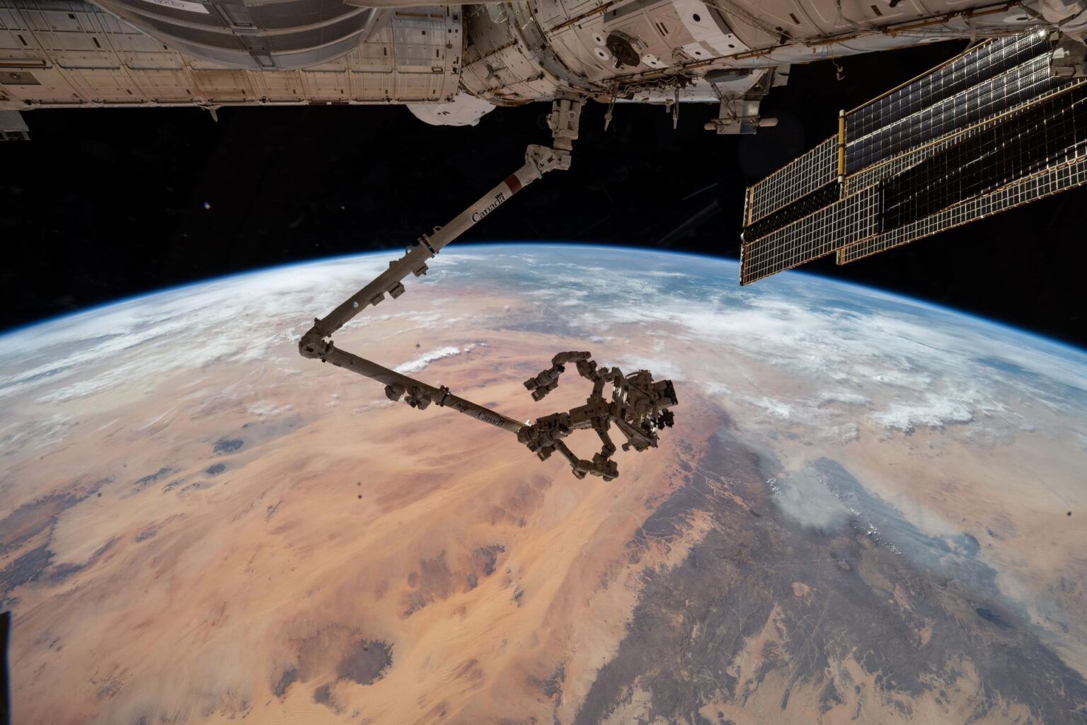 The International Space Station's 57.7-foot-long robotic arm, Canadarm2, with its fine-tuned robotic hand, Dextre, attached is pictured extending from the Harmony module. The orbital outpost was soaring 260 miles above the Saharan Desert in Libya at the time of this photograph.