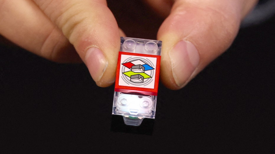 A LEGO component is shown in use during a live product demonstration.