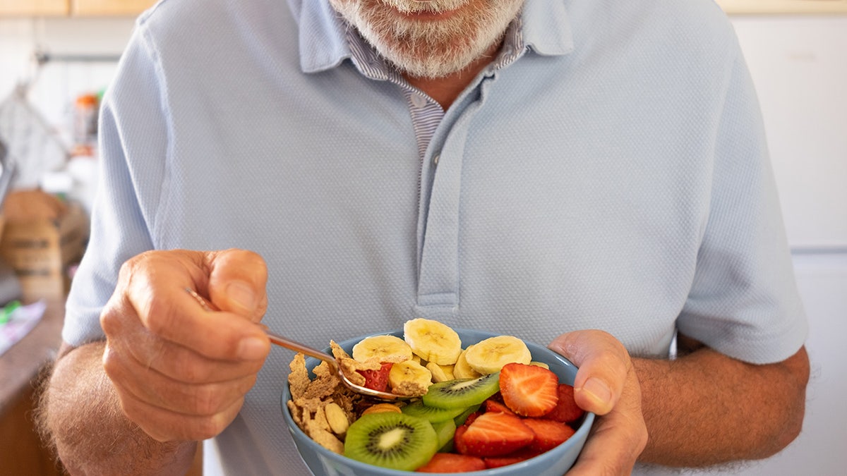 Older man eating fruit salad.