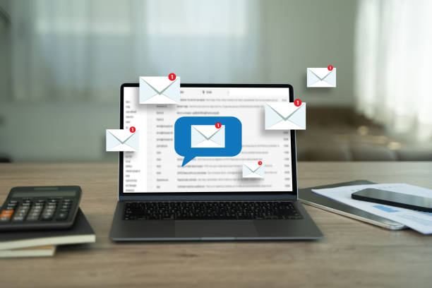 Laptop on a desk showing email messages with notification icons, alongside office items in a bright workspace.