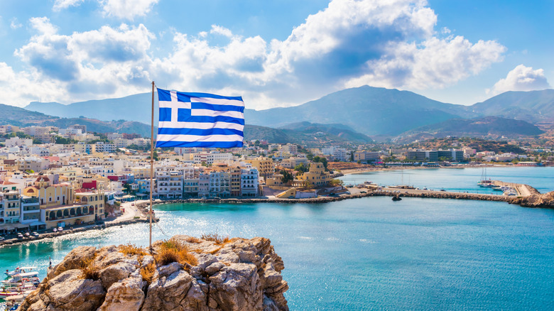 Greek flag blue sky port and buildings of Karpathos