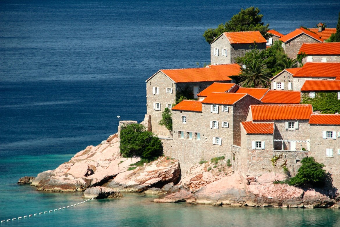 Stone houses with red-tiled roofs on the Adriatic coast in Montenegro, a less-visited destination highlighted in travel trends 2026.