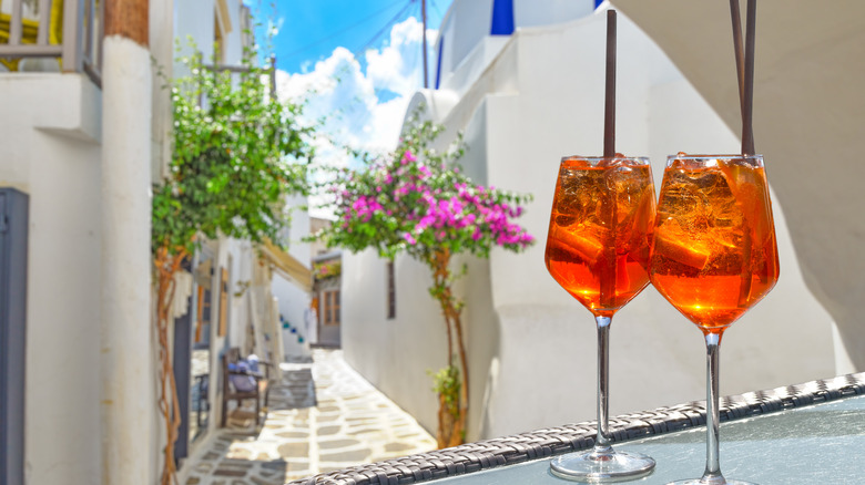 Two glasses of aperol spritz against whitewashed Greek houses