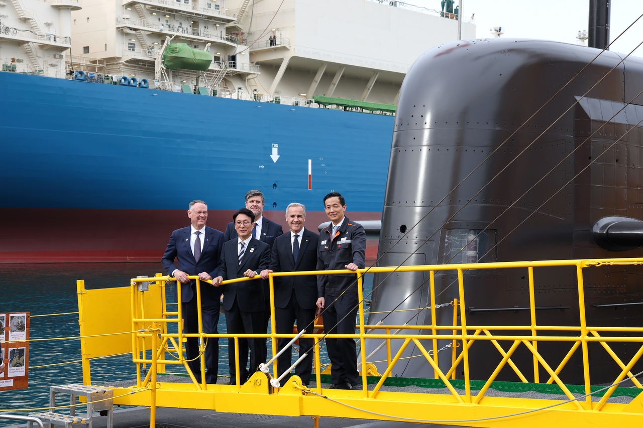 Canadian Prime Minister Mark Carney (front row, third from left), South Korean Prime Minister Kim Min-seok (front row, second from left) and Kim Dong-kwan, vice chair of Hanwha Group (front row, fourth from left), pose aboard the Jang Yeong-sil, a submarine built by Hanwha Ocean, in Geoje, South Gyeongsang Province, on Oct. 30. (Hanwha Ocean)