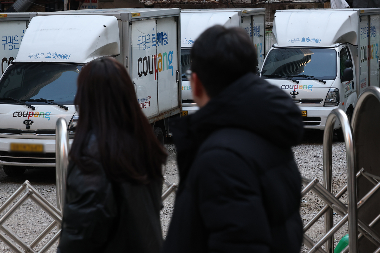 Pedestrians walk by a Coupang delivery van in Seoul. (Yonhap)