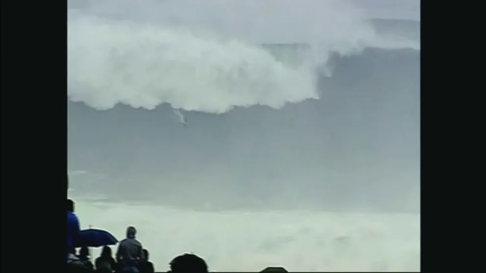 A surfer is towed into a monster wave at Nazaré. 