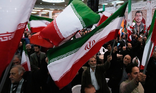 People wave national flags during a ceremony commemorating the death anniversary of the late commander of the Iran