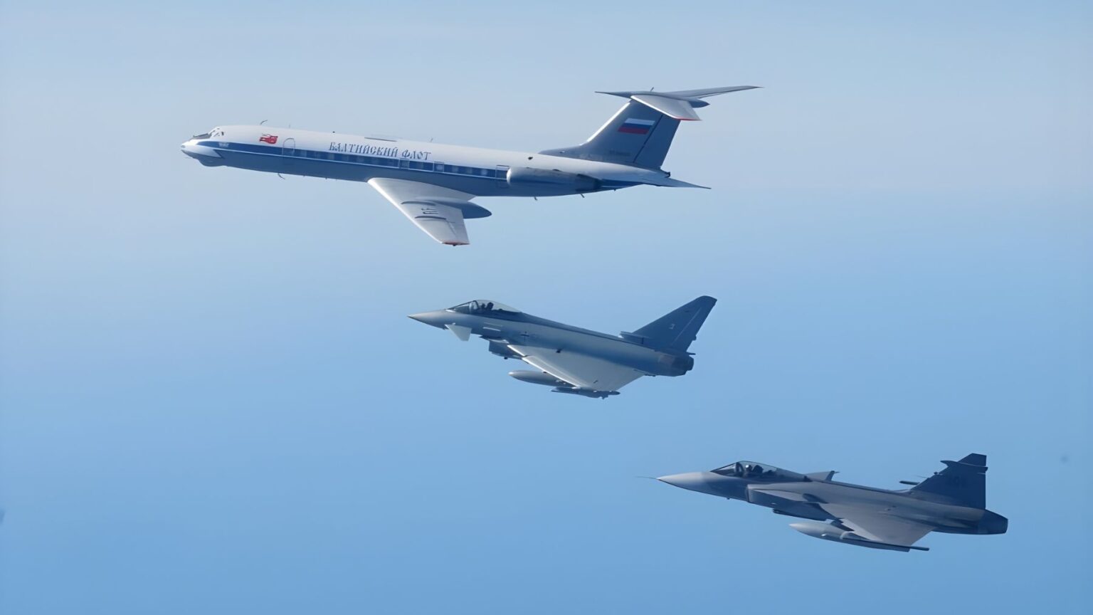 A Russian reconnaissance aircraft flies over the sea while two fighter jets escort it during an interception over the Baltic region.
