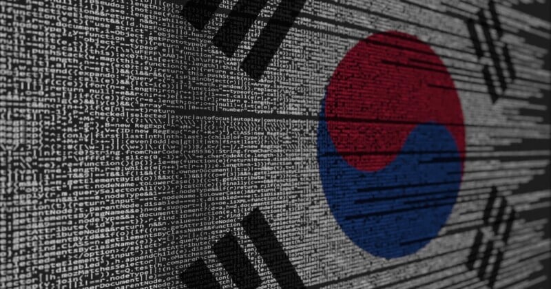 The South Korean flag is overlaid with computer code, symbolizing the intersection of technology and South Korea. The code appears in white, while the flag's colors—red, blue, and black—are clearly visible.