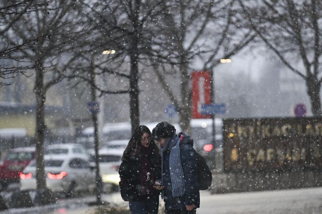 People walk as snow falls in the evening hours in Ankara, Türkiye, on January 22, 2026. (AA Photo)