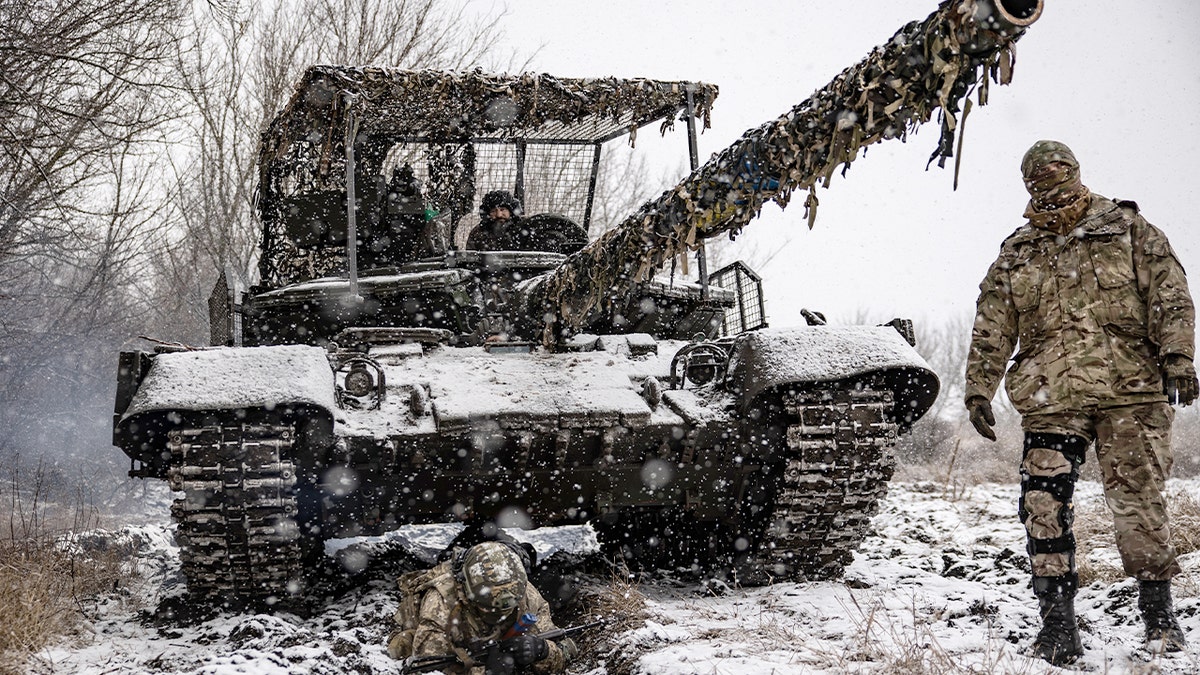 Ukrainian troops train alongside armored vehicles during a coordinated battlefield exercise.