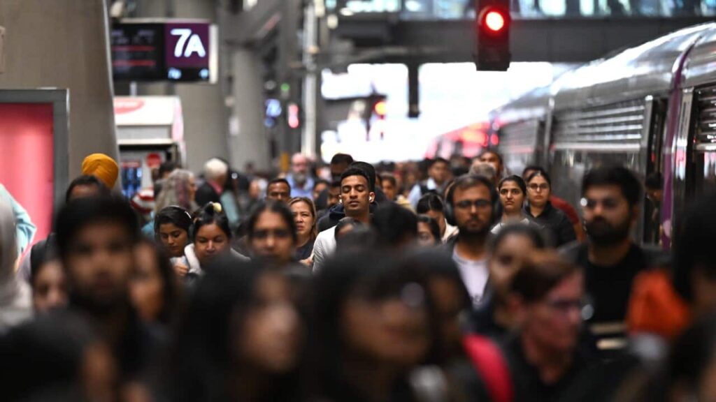 People walking along a busy train platform in a large city