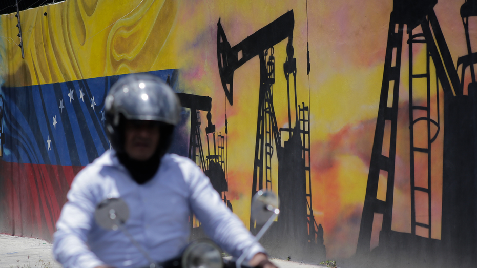 A man rides past a mural depicting Venezuela's oil industry in Caracas, Venezuela.