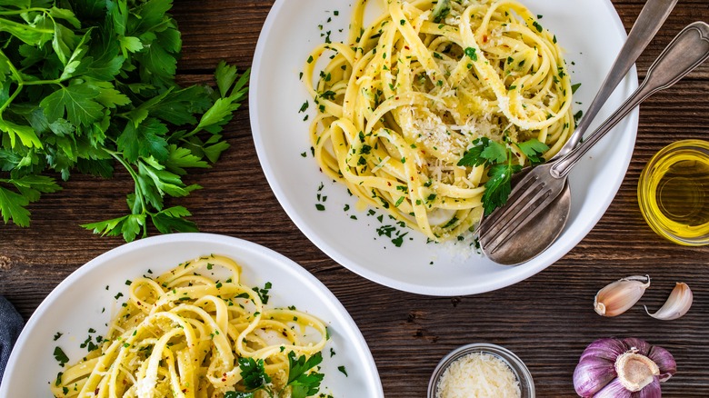 Pasta with garlic, parsley and parmesan cheese on wooden table. Spaghetti aglio olio on wooden background