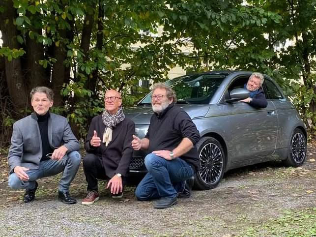 A-ha band members posing with an EV vehicle.