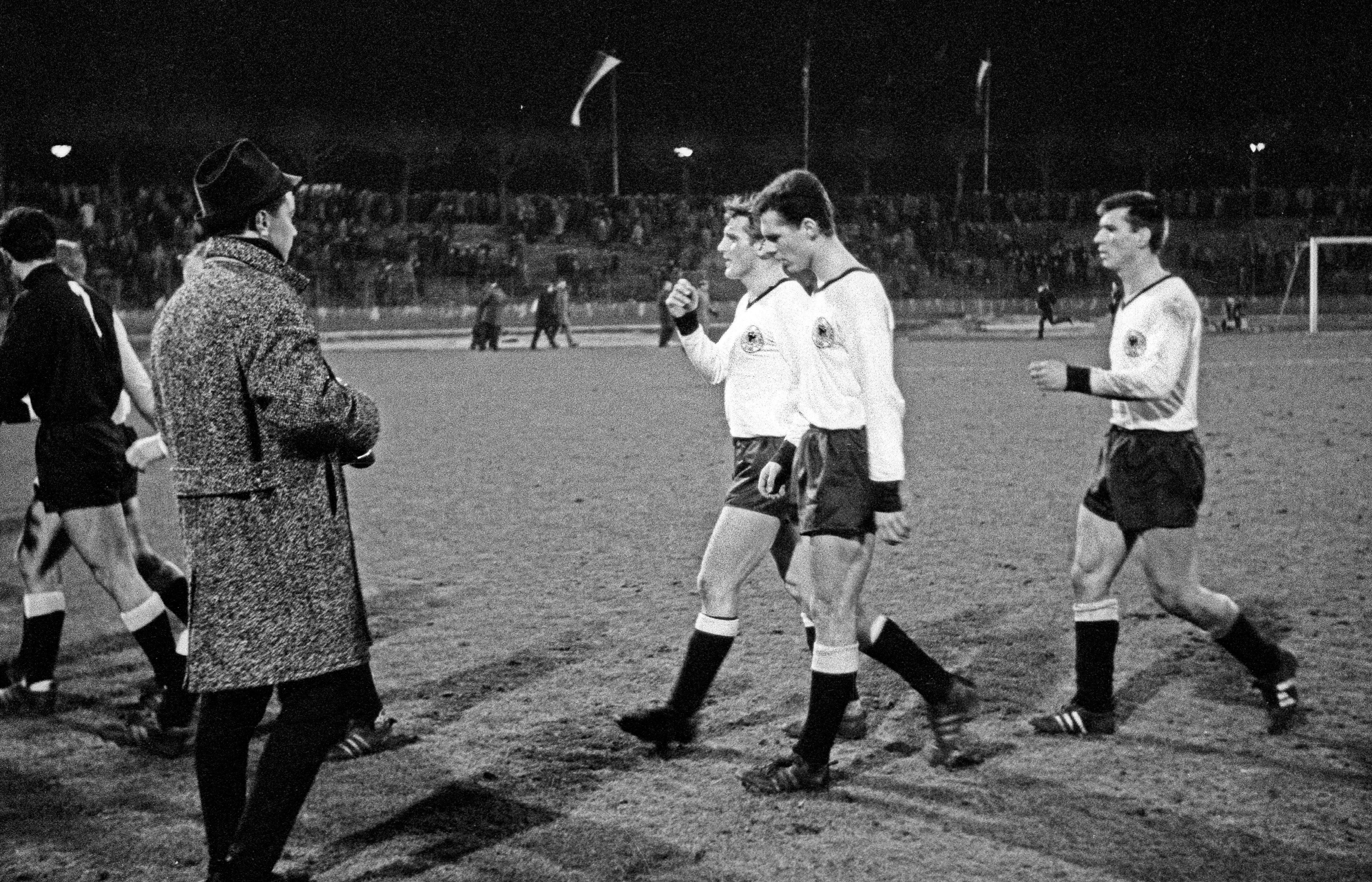 Football players Andreas Brehme, Franz Beckenbauer, and Josef Piontek leave the field after a match.