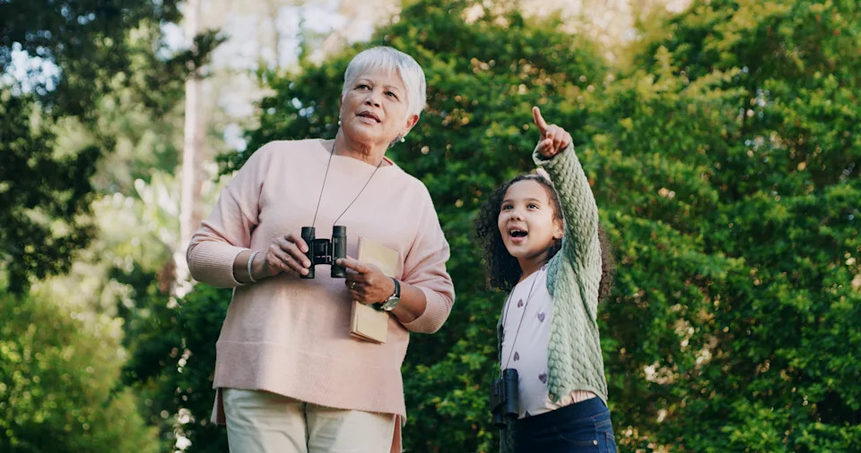 Grandmother, child and binocular in park for travel, sightseeing and pointing with view for bonding. Woman, girl and explore for adventure, bird watching or together in nature with family in Mexico