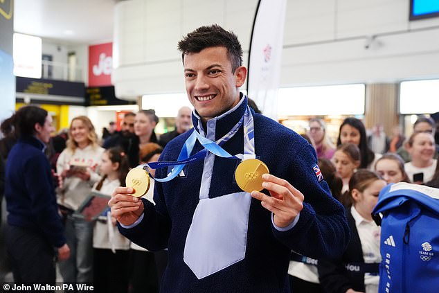Matt Weston poses with the two gold medals he won after arriving back at Gatwick Airport