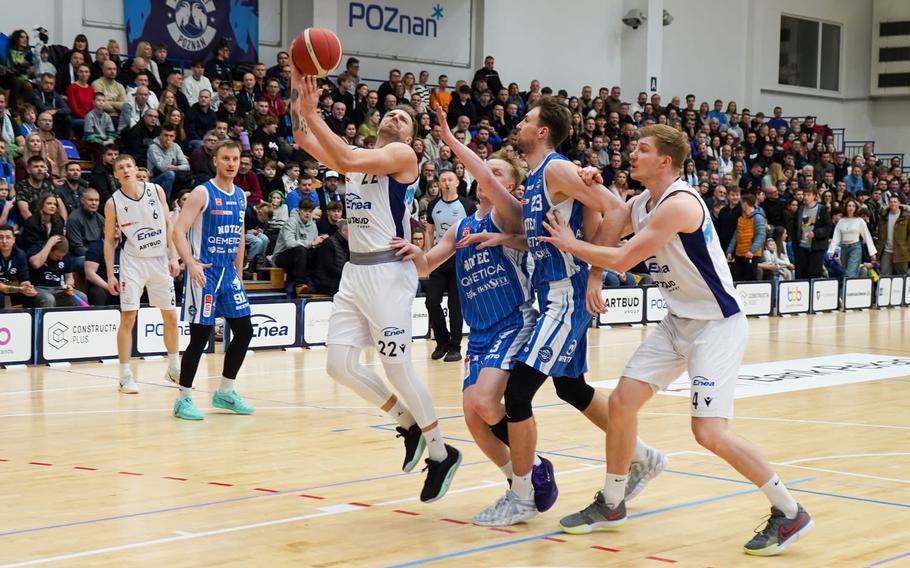 An Enea Poznan Basket player drives to the basket through traffic.