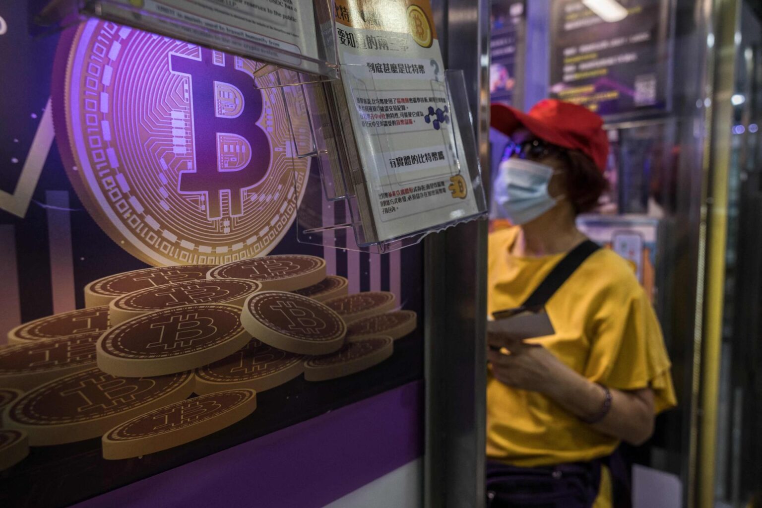A woman speaks with a worker at a cryptocurrency exchange in Hong Kong, April 2024. AFP-Yonhap
