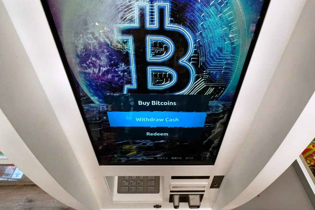 A Bitcoin logo on the display screen of a cryptocurrency ATM, showing options to "Buy Bitcoins" and "Withdraw Cash."
