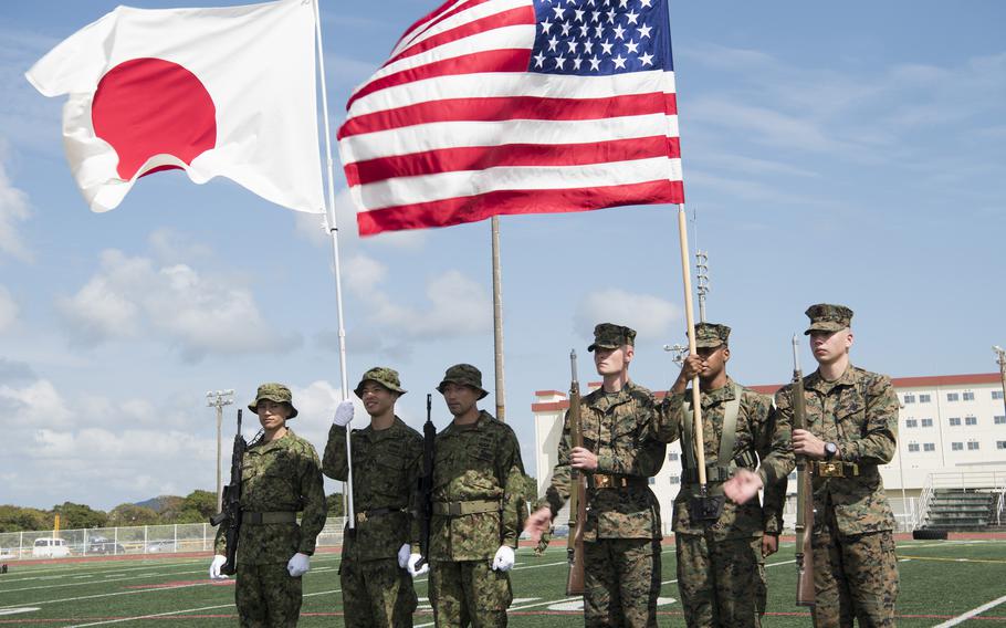 The Japanese flag and the American flag are held by a color guard.