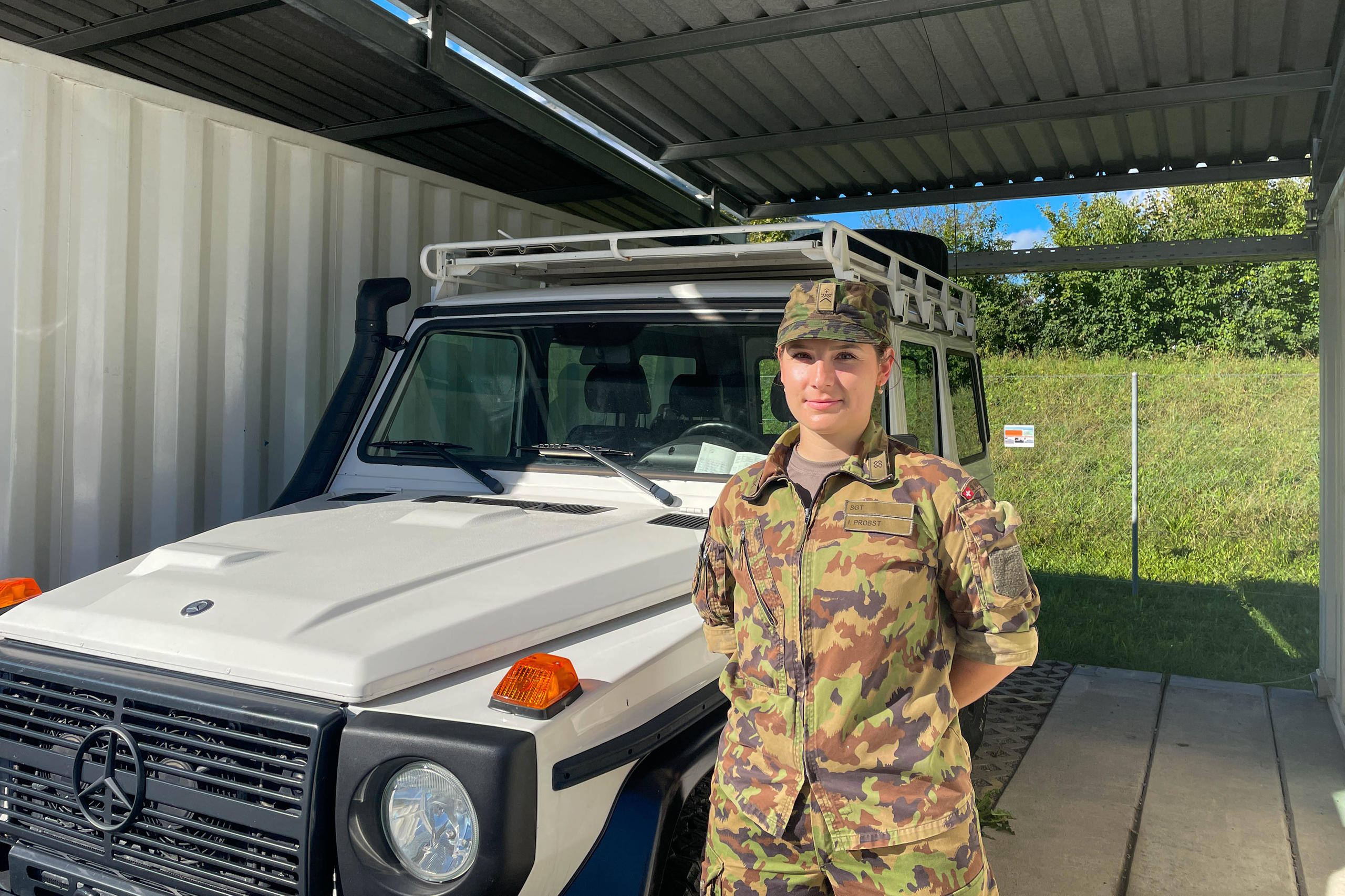 A woman soldier standing in front of a military car