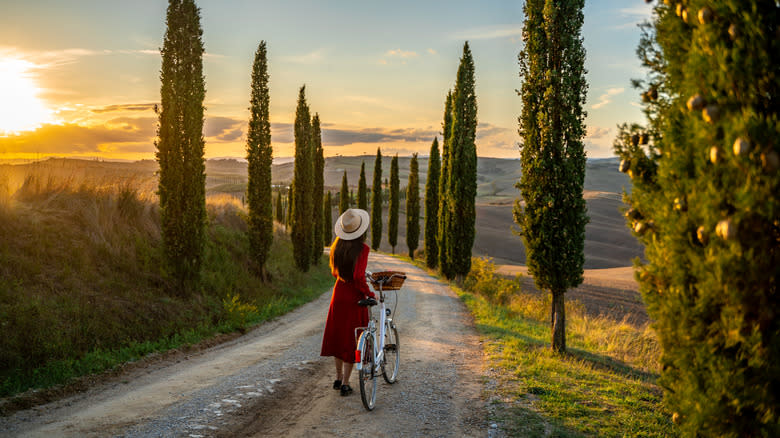 A girl with a bike in Tuscany at sunset.