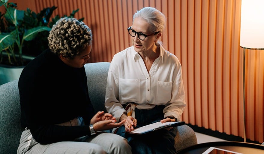 How to Build Your Business Case for a Better Mental Health Solution in the Workplace A woman in a black sweater working with a therapist in a white button down