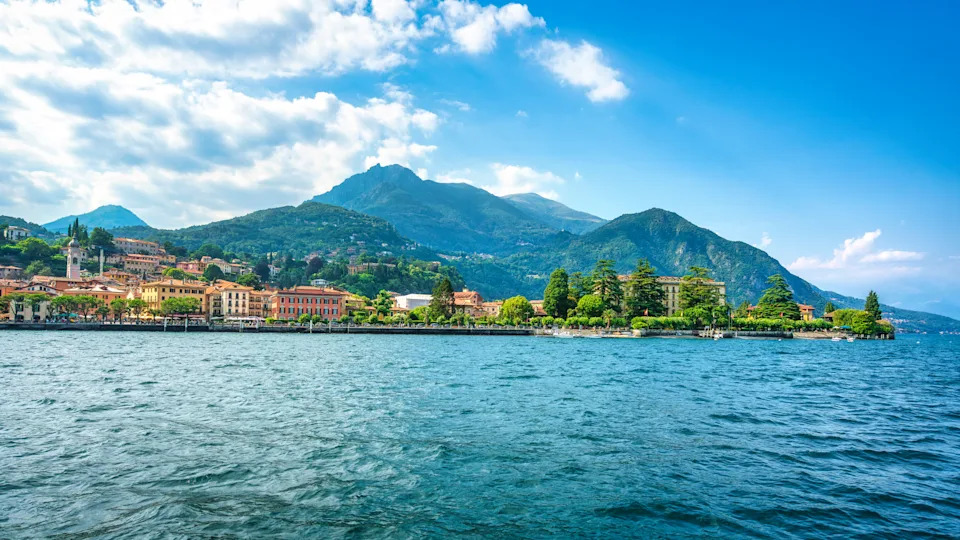 Panoramic view of the charming town of Menaggio on the western shore of Lake Como, Lombardy, Italy. Historic buildings line the waterfront promenade.