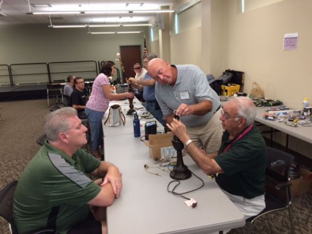 Volunteers work as a team at a previous Repair Cafe to fix a broken lamp. (FILE)