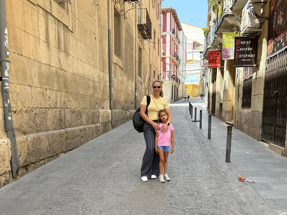 Izabela Oquendo and her young daughter stand in the middle of a Spanish street.