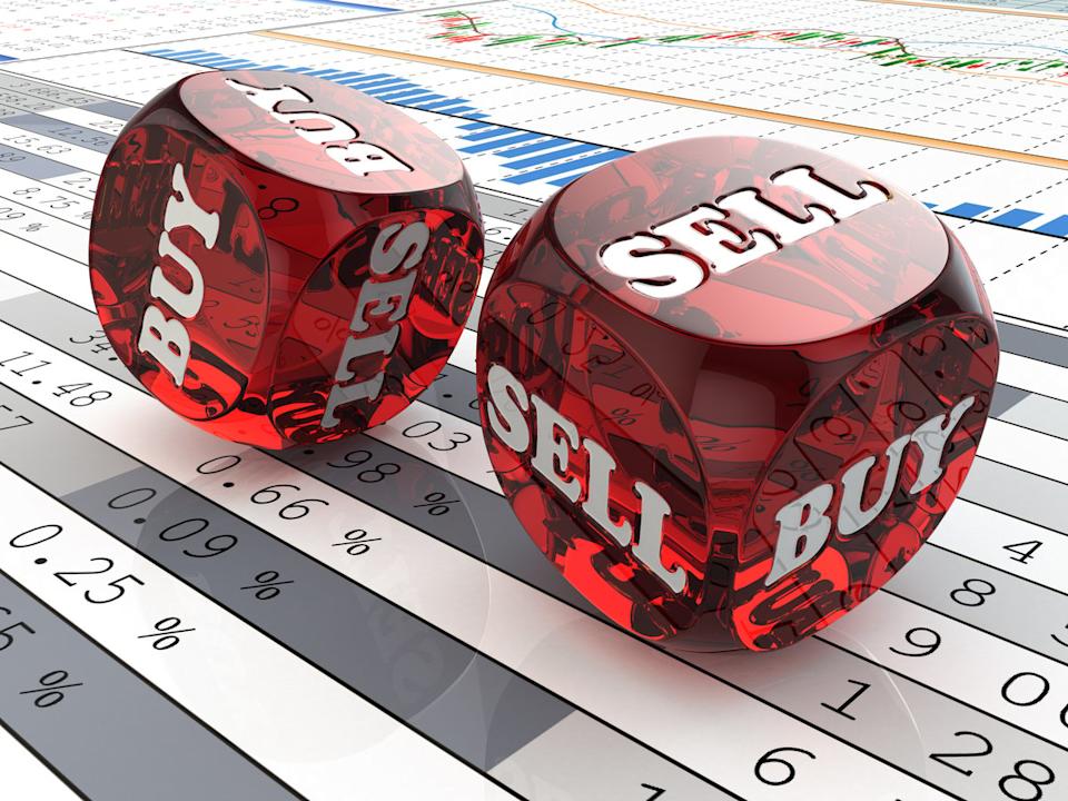 Dice with the words Buy and Sell printed on them laying on a printout of financial data.