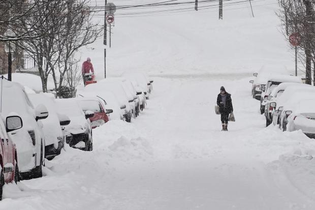 FILE - A person carries grocery bags up a residential street during a winter storm Jan. 25, 2026, in Cincinnati. (AP Photo/Joshua A. Bickel, File)