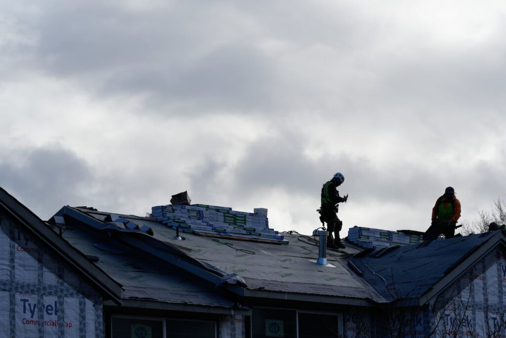 Construction workers stand on the roof of a building as they work in Hillsboro, Ore.