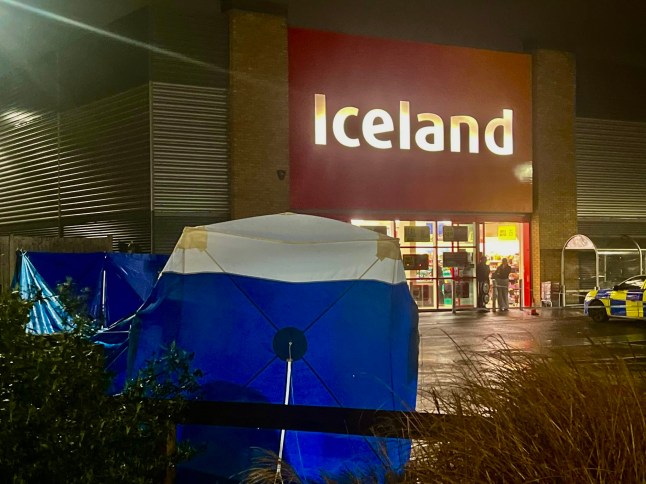 A murder investigation has been launched after a woman was found dead in a supermarket car park in Slough. Emergency services were called to the car park of an Iceland store earlier today following reports of concern for the welfare of a woman. Upon arrival, officers discovered the body of a woman, and the death is now being treated as suspicious. Thames Valley Police have since confirmed that a murder investigation is underway, with specialist officers and forensic teams deployed to the scene. A blue and white forensic tent has been erected in the car park, while a large police cordon remains in place as investigators carry out detailed examinations. Officers have also been seen speaking with potential witnesses and reviewing CCTV footage from surrounding businesses. The area remains sealed off to members of the public, with police vehicles and crime scene investigators continuing to work late into the evening. At this stage, no formal identification of the victim has been released, and it is not yet known whether any arrests have been made. A spokesperson for Thames Valley Police is expected to issue a full statement once initial enquiries have progressed. Residents and shoppers in the area have reported a significant police presence, with some describing the scene as ?shocking? and ?deeply concerning.? Anyone who may have information relating to the incident is urged to contact Thames Valley Police, quoting the relevant incident reference once released.