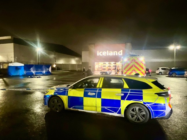 A murder investigation has been launched after a woman was found dead in a supermarket car park in Slough. Emergency services were called to the car park of an Iceland store earlier today following reports of concern for the welfare of a woman. Upon arrival, officers discovered the body of a woman, and the death is now being treated as suspicious. Thames Valley Police have since confirmed that a murder investigation is underway, with specialist officers and forensic teams deployed to the scene. A blue and white forensic tent has been erected in the car park, while a large police cordon remains in place as investigators carry out detailed examinations. Officers have also been seen speaking with potential witnesses and reviewing CCTV footage from surrounding businesses. The area remains sealed off to members of the public, with police vehicles and crime scene investigators continuing to work late into the evening. At this stage, no formal identification of the victim has been released, and it is not yet known whether any arrests have been made. A spokesperson for Thames Valley Police is expected to issue a full statement once initial enquiries have progressed. Residents and shoppers in the area have reported a significant police presence, with some describing the scene as ?shocking? and ?deeply concerning.? Anyone who may have information relating to the incident is urged to contact Thames Valley Police, quoting the relevant incident reference once released.