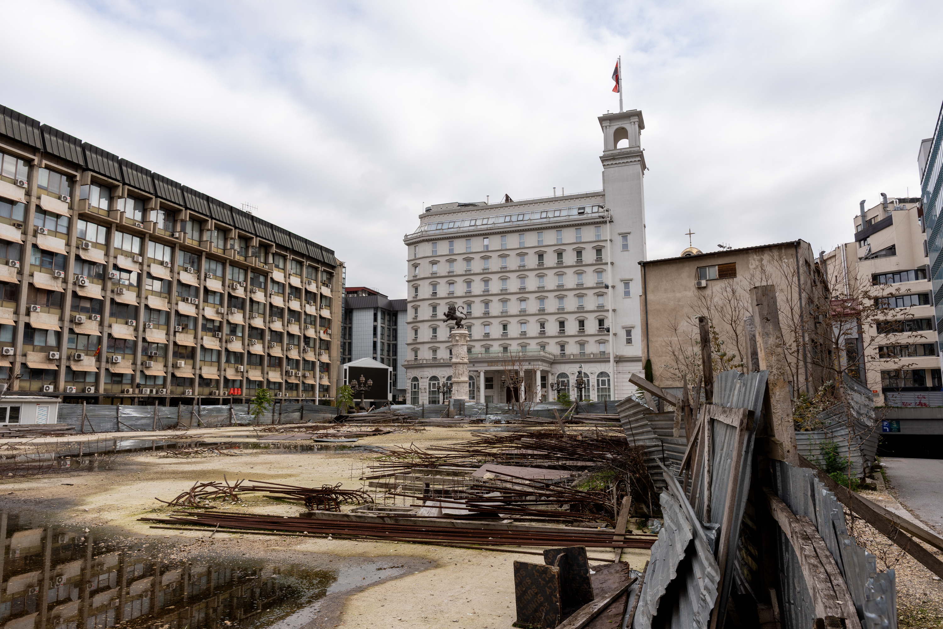 Large white building with a flag on the roof, construction site in the foreground