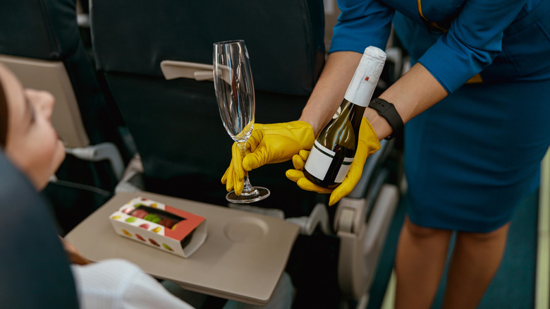 Female flight attendant offering wine to passenger