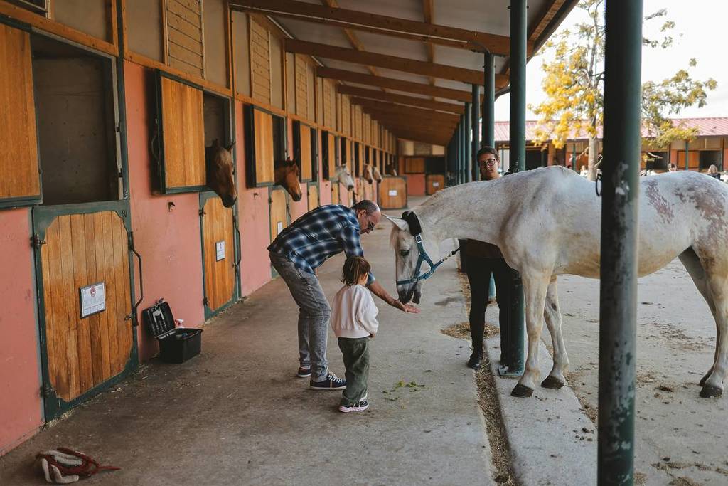 A man and child petting a horse at the stable