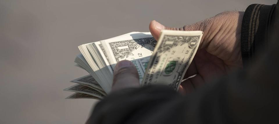 A currency exchanger counts U.S. dollar bills, while Americans remain split over whether the economy is on the right track or not.