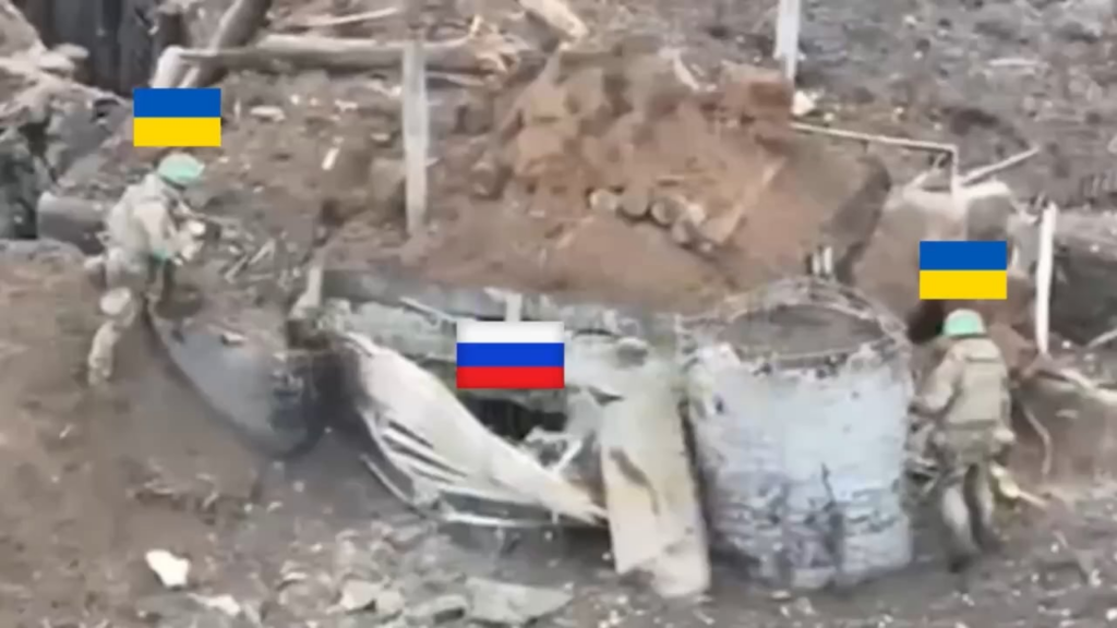 2 Ukrainian soldiers are positioned outside a bunker occupied by a Russian soldier. One of them throws an explosive charge inside. As the Russian soldier attempts to throw it back out, it detonates.