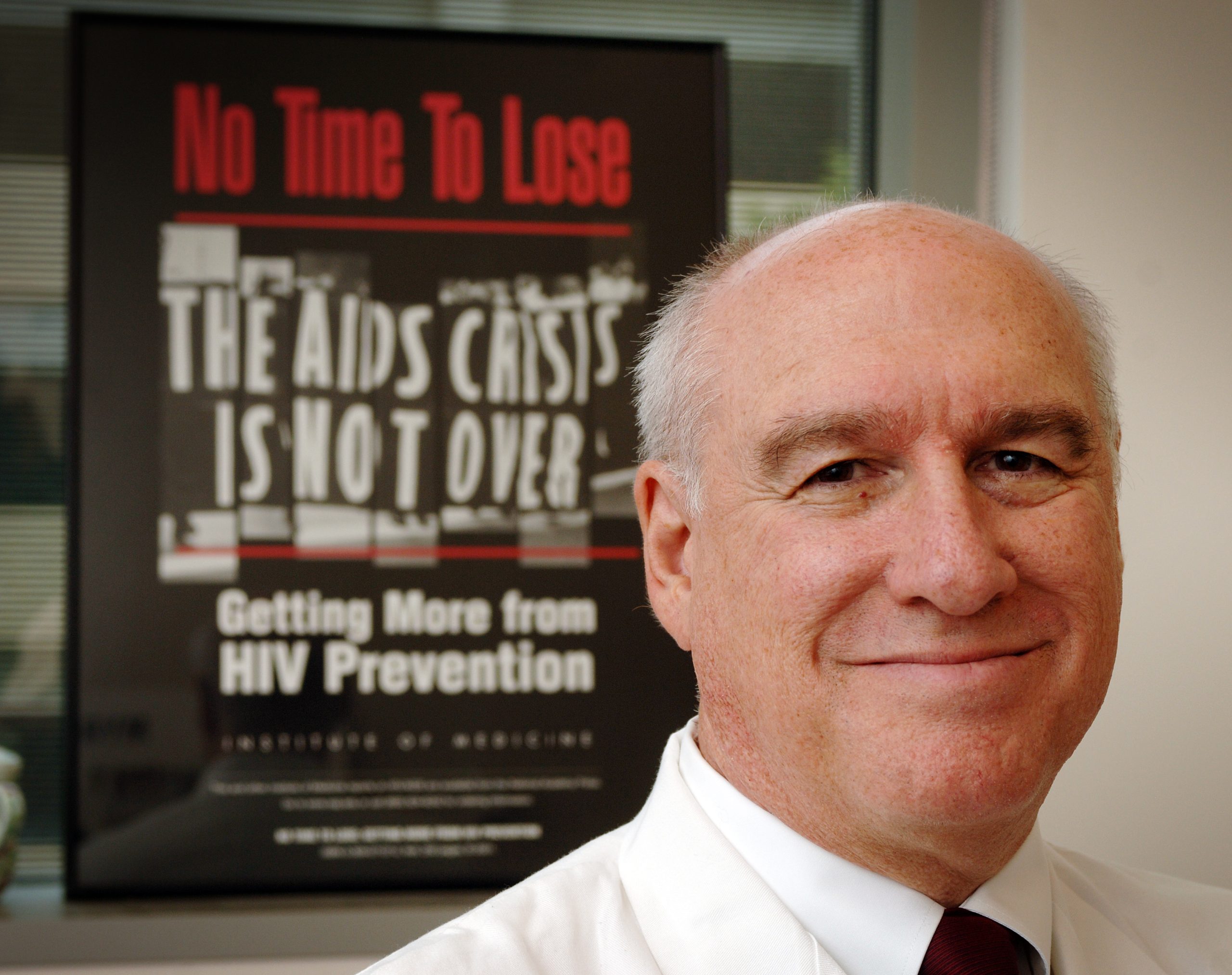 Myron Cohen in his office at the Bioinformatics Building at the University of North Carolina at Chapel Hill in front of a poster advertising his book, "No Time To Lose" about the AIDS crisis